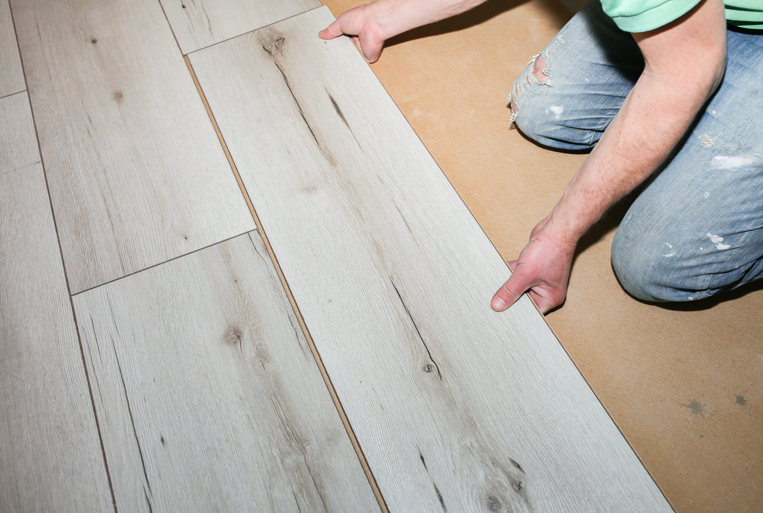 Worker making laminate flooring in apartment. Maintenance repair renovation. Wooden parquet planks indoors.