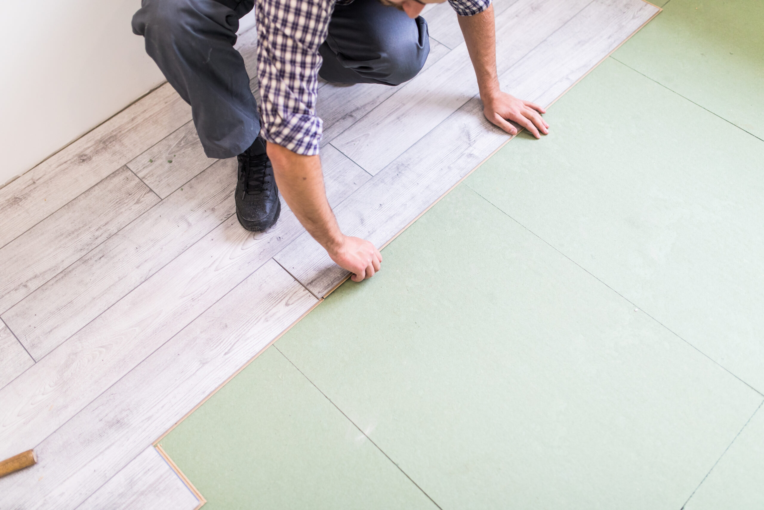 Young worker laying a floor with bright laminated flooring boards